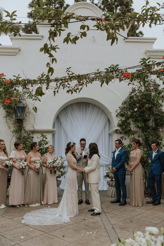 Wedding ceremony with the bride and groom in the center, in front of an archway with flowers for Ivanka & Victoria's Wedding
